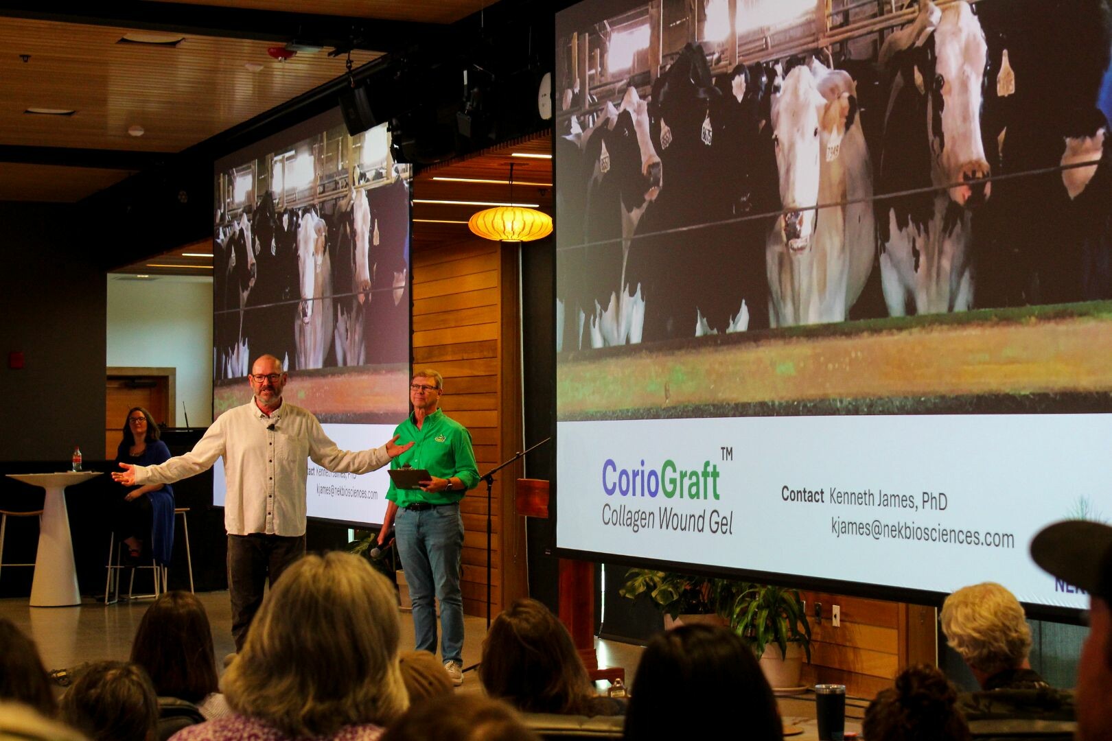 Two presenters discuss a product, CorioGraft, with a cow image on the screen behind them.