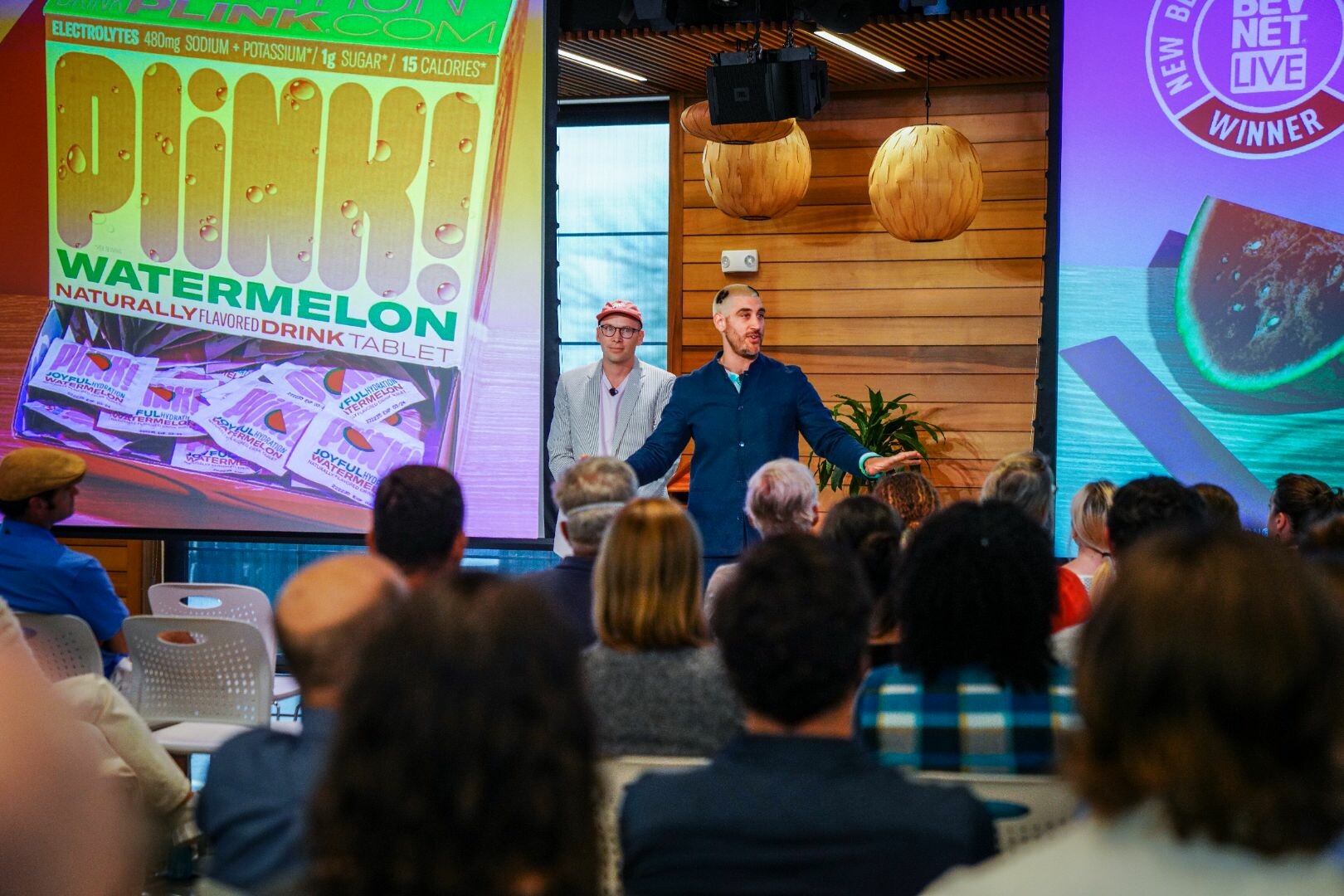 Presentation featuring two speakers promoting PLINK! Watermelon drink tablets to an audience.