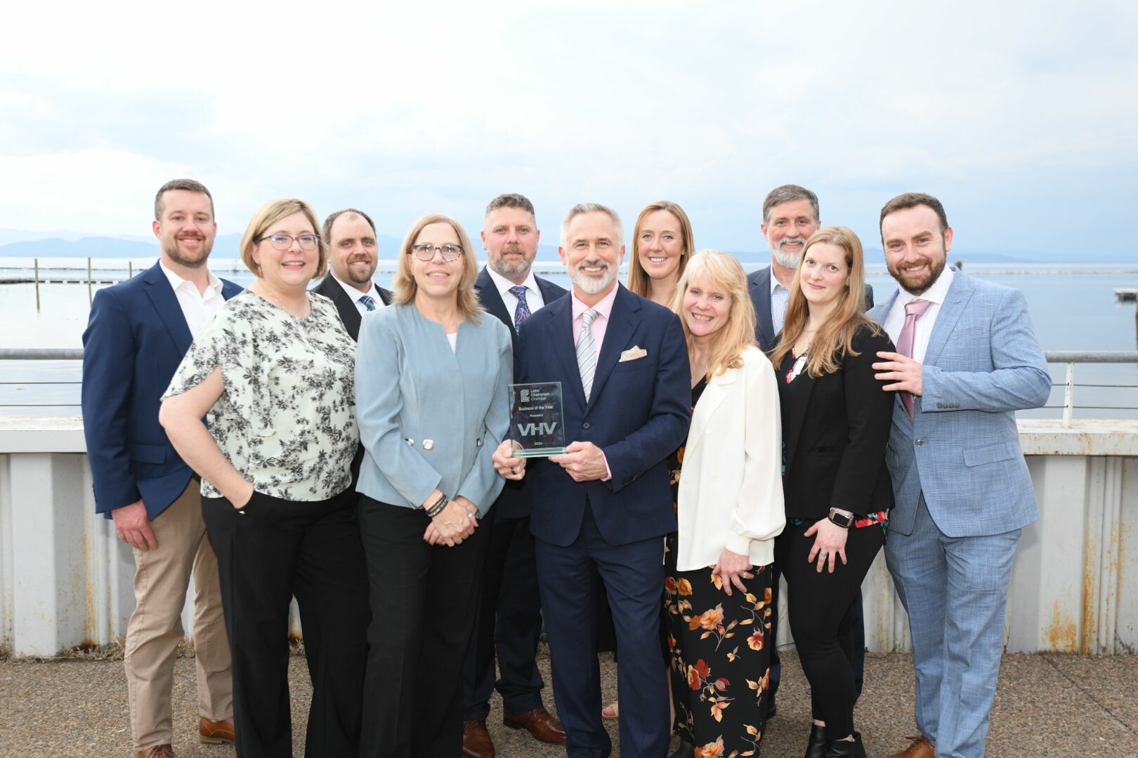 Group of professionals posing by the water with an award, smiling for the photo.