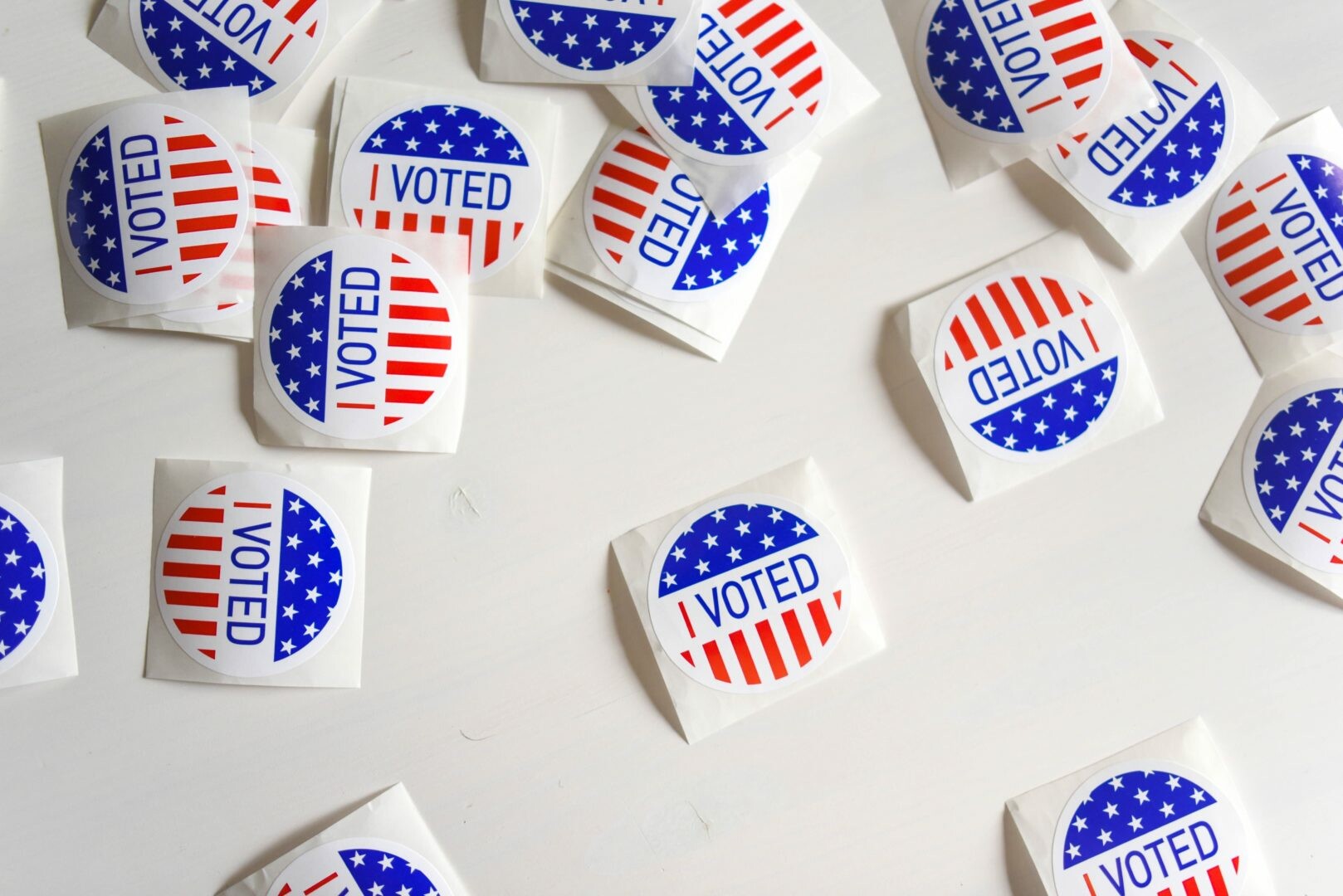 Scattered "I Voted" stickers with red, white, and blue designs on a white surface.