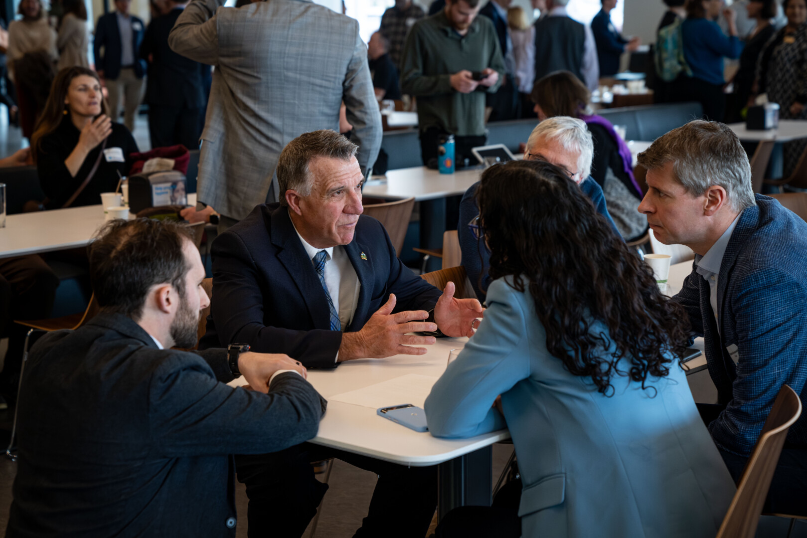 A group of people engaged in conversation around a table at a networking event.
