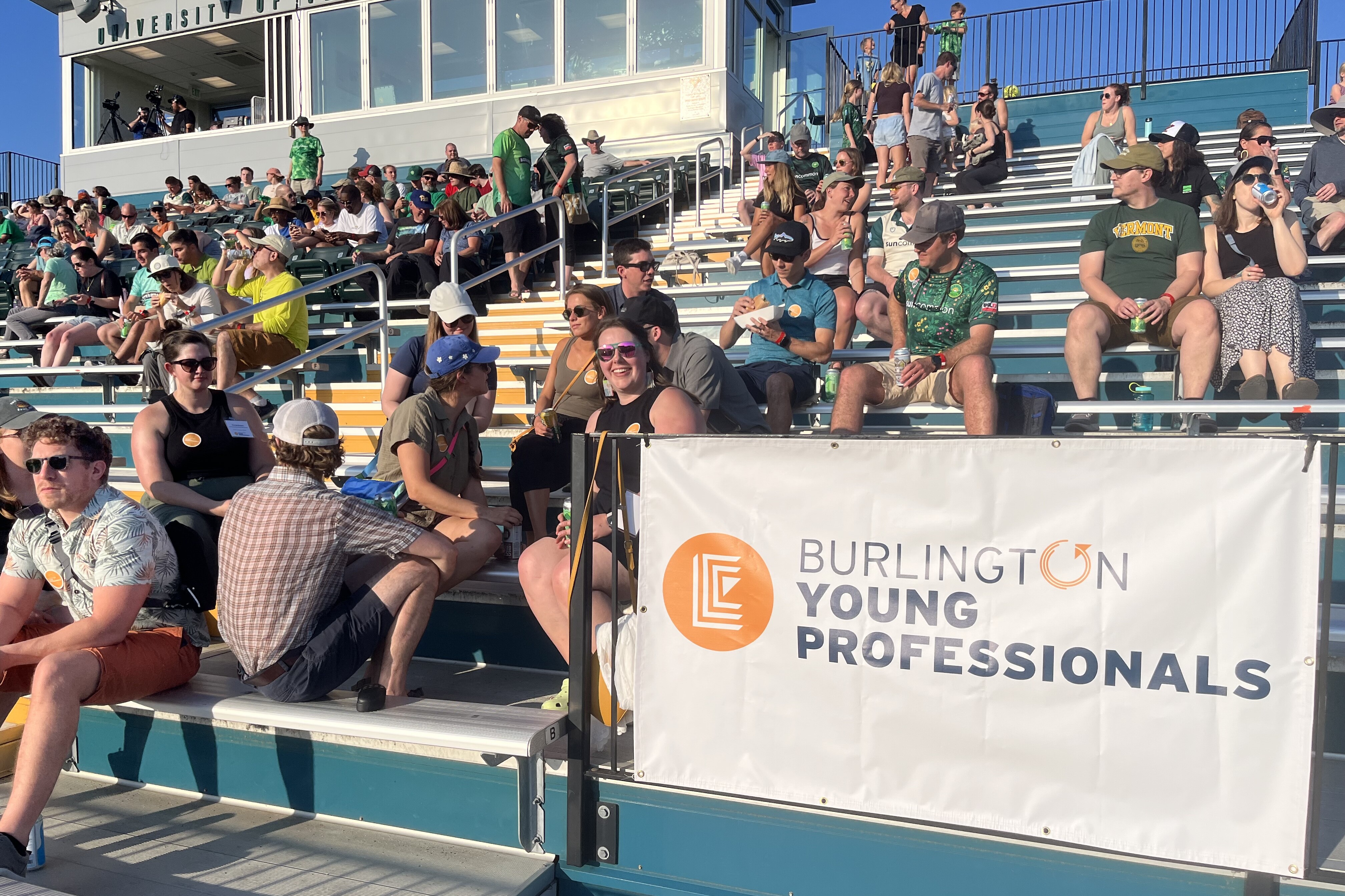 Crowd of people in stadium seats, with a banner for Burlington Young Professionals.
