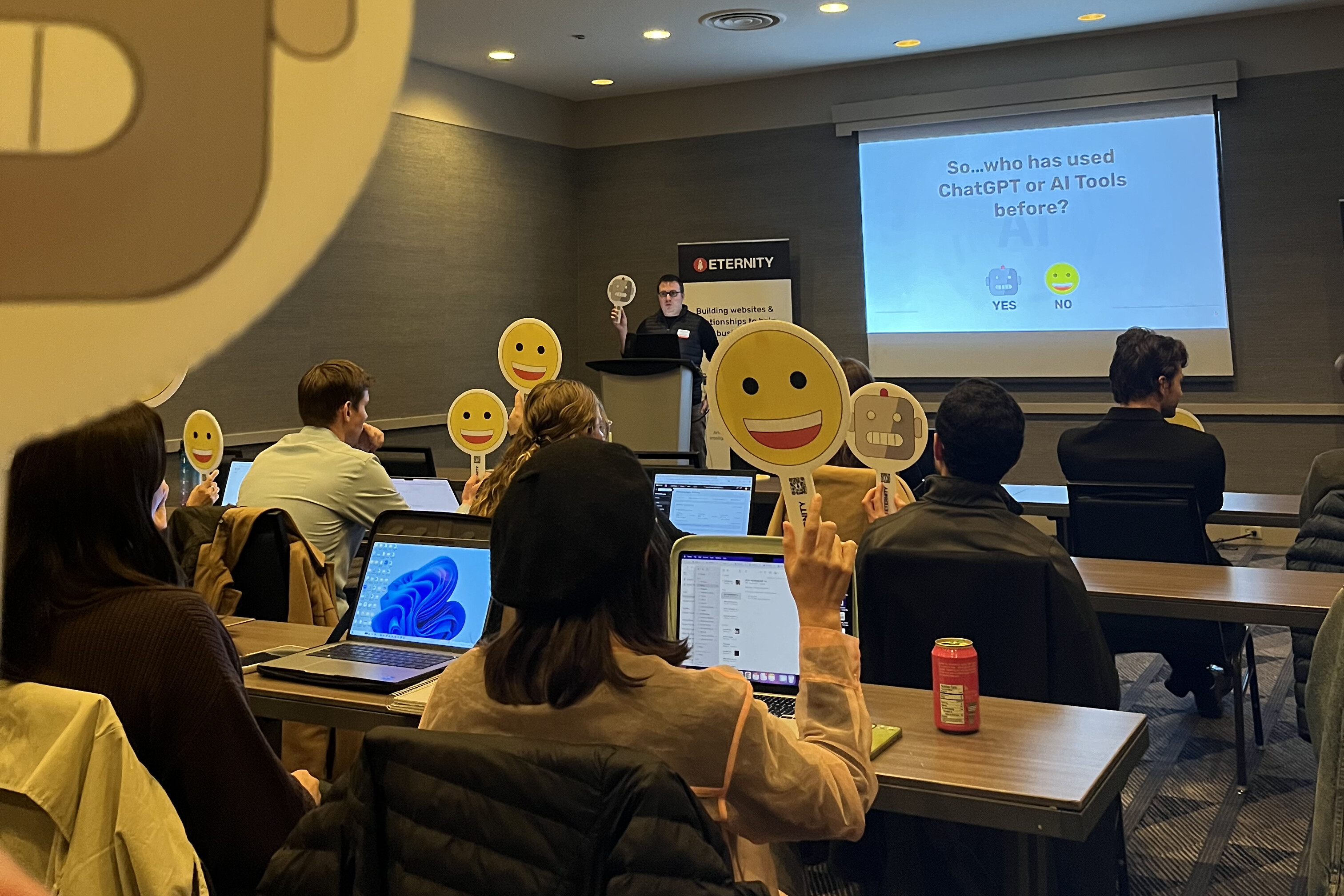 Audience participating in a presentation about ChatGPT and AI tools, holding emoji signs.