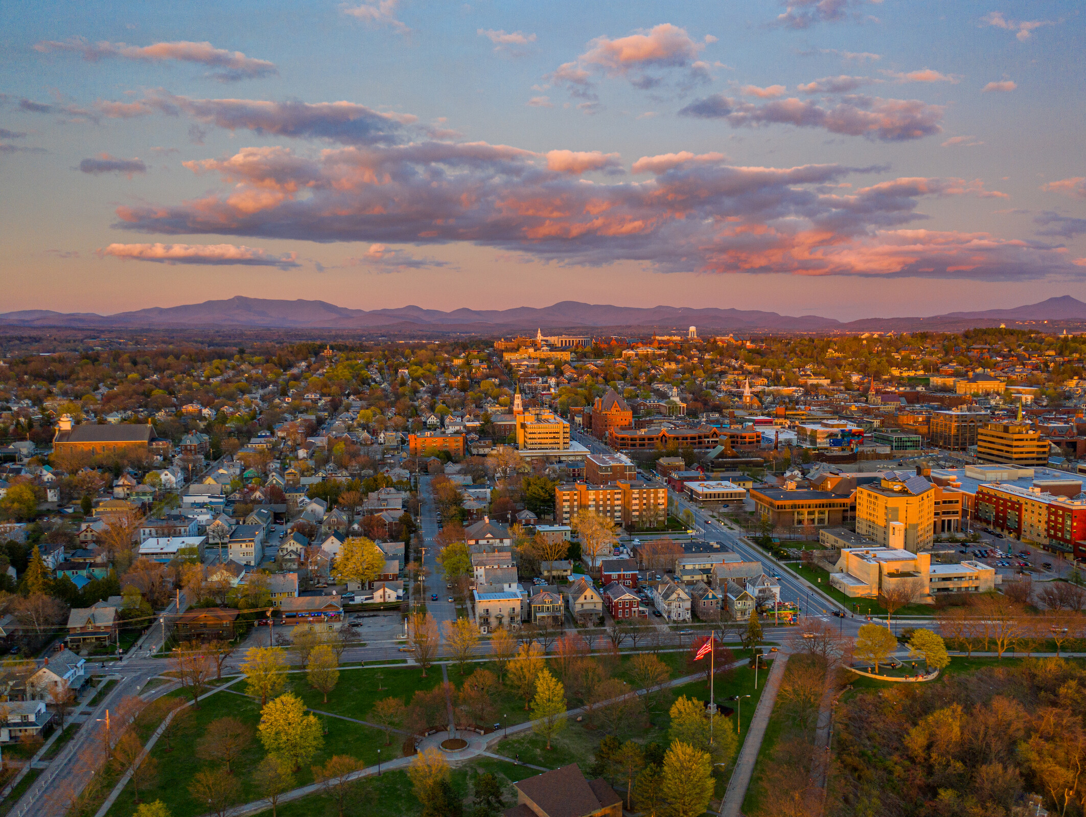 Aerial view of a Burlington Vermont at sunset with mountains in the background.