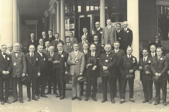 Group photo of men in suits, gathered outside a building, likely from a conference in 1920.