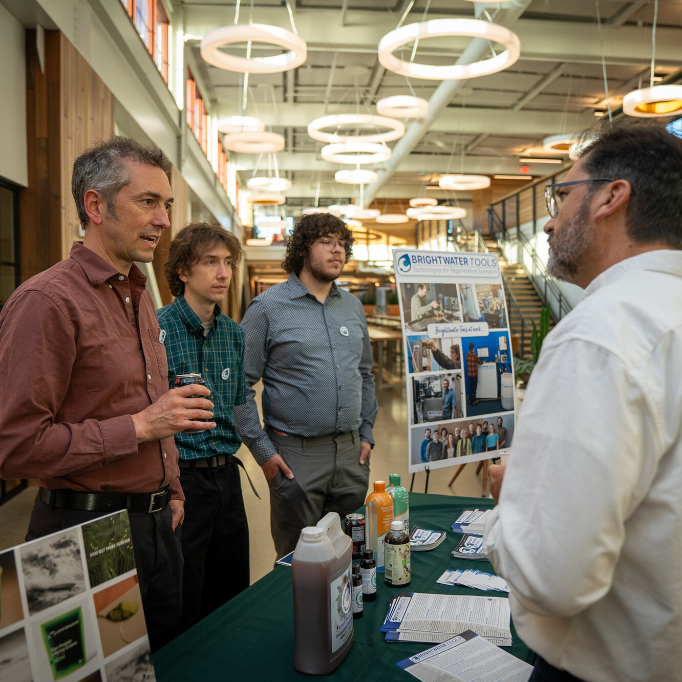 Four individuals engage at a booth for BrightWater Tools, discussing products and technology.