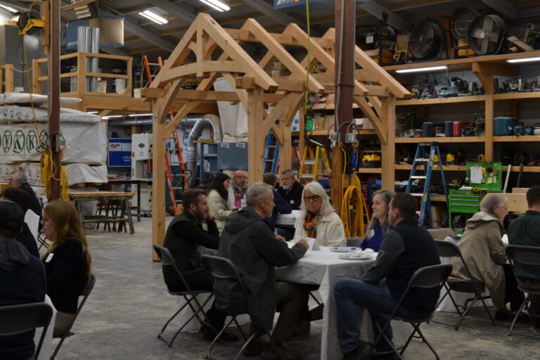 Attendees networking at an LCC business event inside a Vermont woodworking and trades facility