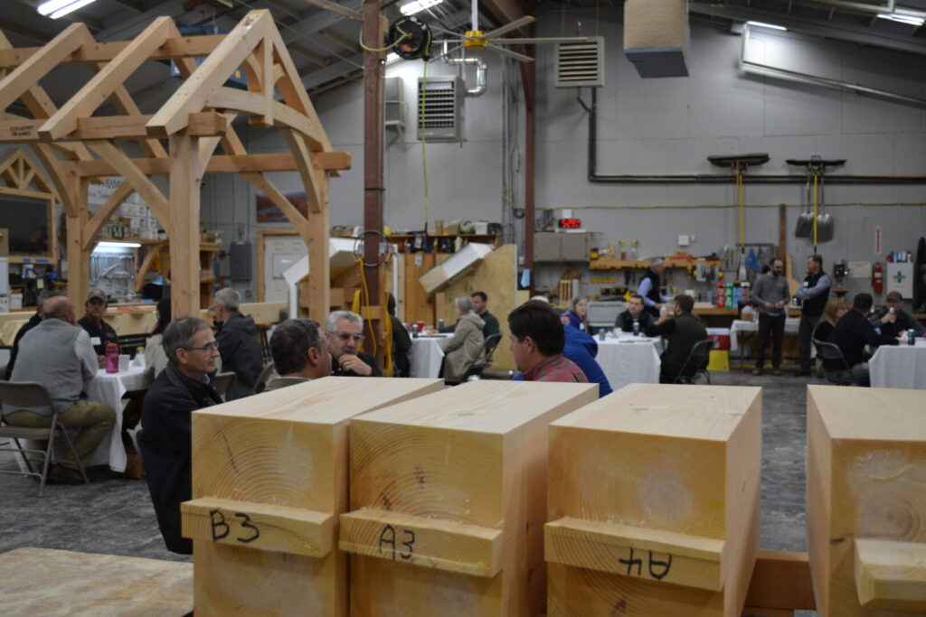 Attendees networking during an LCC business event inside a Vermont timber framing workshop