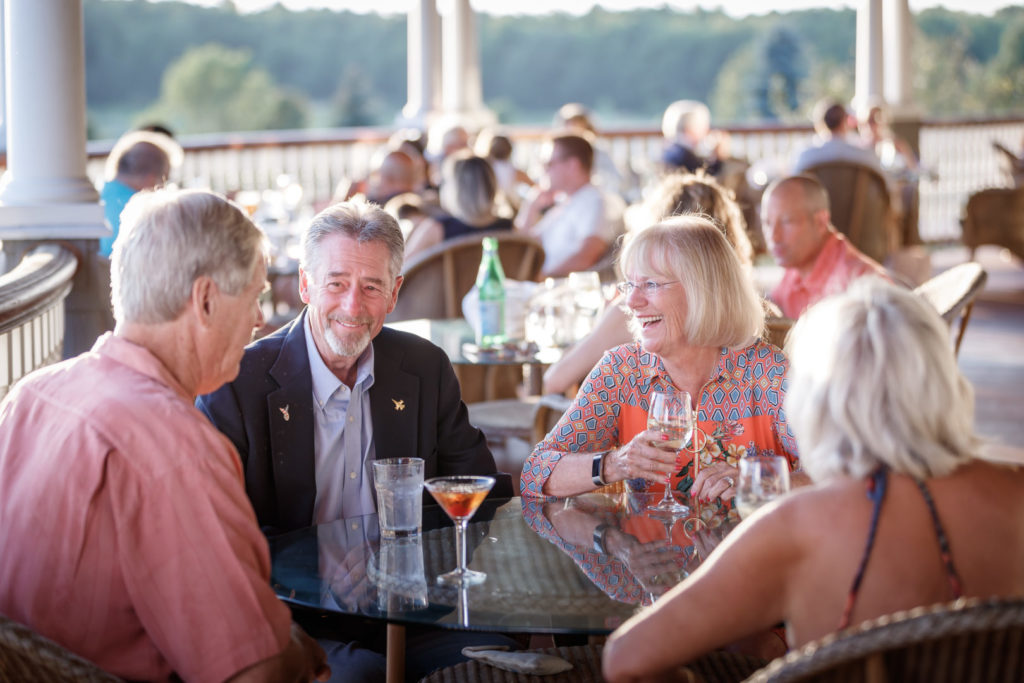 photo of group of people dining around a table at vermont national country club outside on a sunny day