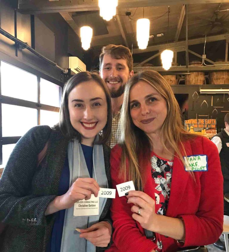 photo of three young professionals wearing nametags smiling for the camera