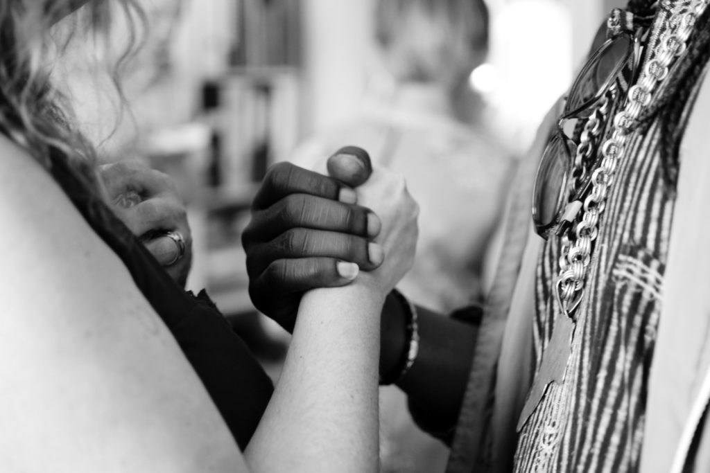 a white women and black women holding hands in a black and white photo
